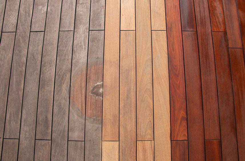 Outdoor wood decking showing a refinished surface transitioning from weathered gray to restored, rich brown tones