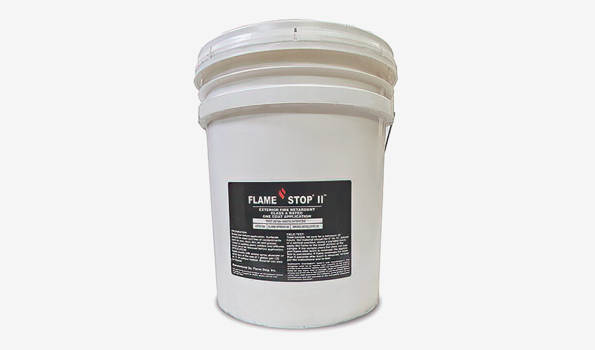 Bucket of fire-retardant exterior paint labeled Flame Stop II, designed for fireproofing homes and reducing wildfire risks