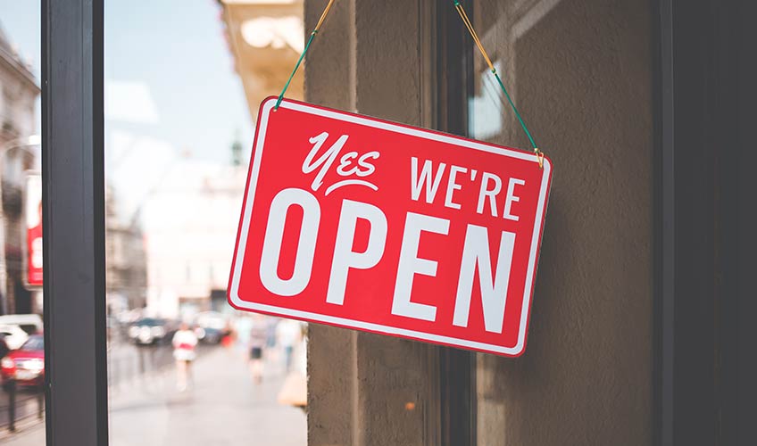 Red 'Yes, We're Open' sign displayed on a storefront window, symbolizing business readiness and community support.